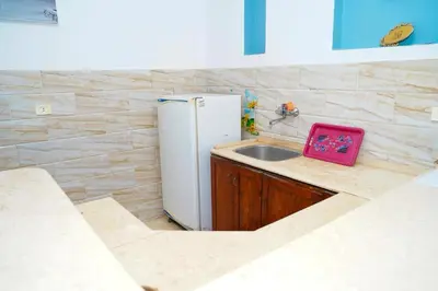 a kitchen with a white refrigerator and a sink at Aisha Guest House And Restaurant in Al Aqālitah