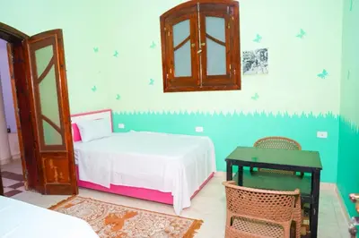 a bedroom with a bed and a table and a mirror at Aisha Guest House And Restaurant in Al Aqālitah