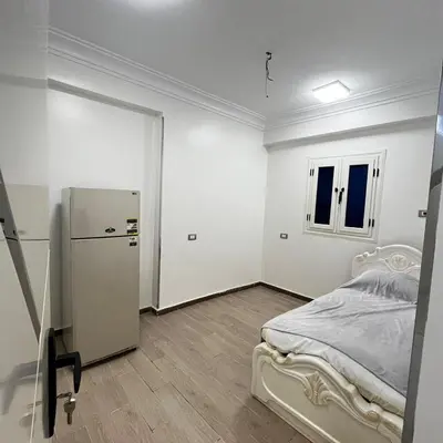 a white room with a bed and a refrigerator at FUN MBASSY DELUXE APARTMENT ASWAN down town in Aswan