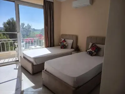 two beds in a room with a large window at Karima's house B in Al Aqālitah