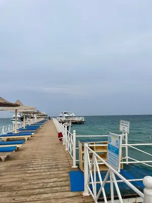 a wooden pier with blue benches on the ocean at Family-Friendly Studio, Beach and Pools Access in Hurghada