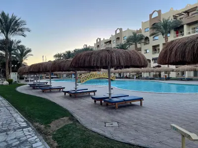 a group of benches with umbrellas and a swimming pool at Family-Friendly Studio, Beach and Pools Access in Hurghada