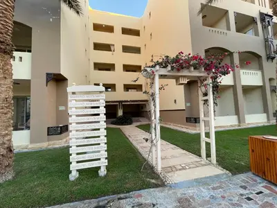 a garden in front of a building with a pergola with flowers at Family-Friendly Studio, Beach and Pools Access in Hurghada