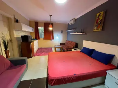 a bedroom with a red bed and a living room at Family-Friendly Studio, Beach and Pools Access in Hurghada
