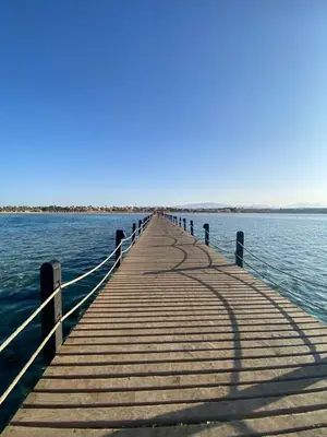 a wooden pier sticking out into the water at Cozy Chalet In Stella Makadi Beach Resort Hurghada in Hurghada