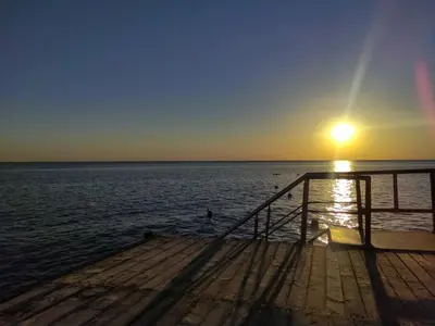 a pier with the sun setting over the water at Cozy Chalet In Stella Makadi Beach Resort Hurghada in Hurghada