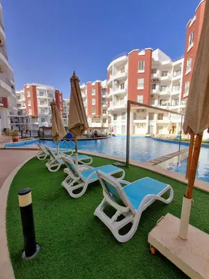 a group of lounge chairs and umbrellas next to a swimming pool at Aqua Palms Resort Hurghada in Hurghada