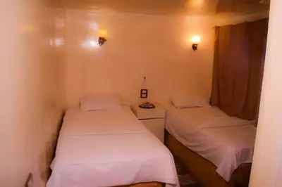 two beds in a small room with white sheets at Water Lily in Luxor