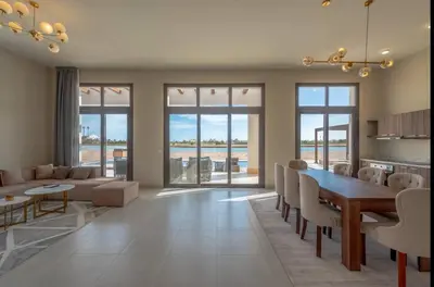 a living room with a dining room table and chairs at Stunning Villa with breathtaking golf & lake view in Hurghada