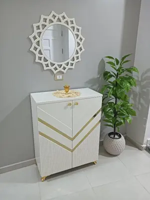 a white cabinet with a mirror and a potted plant at noreno house in Shellal