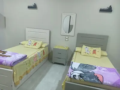 a bedroom with two beds and a mirror at noreno house in Shellal