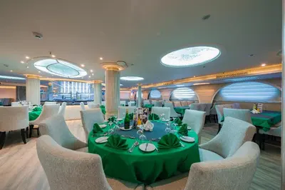 a dining room with a green table and chairs at فندق نايل ستوري سوهاج in Suwhaj