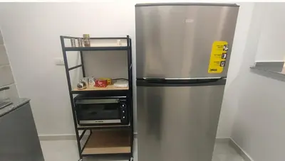 a stainless steel refrigerator with a microwave on a shelf at Desert Daisy in Luxor