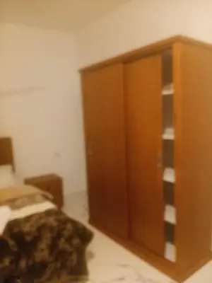 a bedroom with a wooden cabinet next to a bed at Habu Palace home in Luxor
