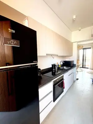 a kitchen with a black refrigerator and white cabinets at EL GOUNA Boho Beach Chalet with pool access in Hurghada