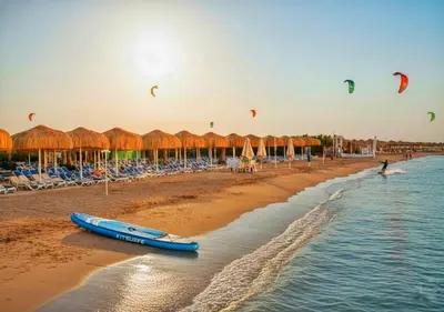 a blue surfboard laying on the beach with kites at Fanadir Bay Beach Resort & Aqua Park in Hurghada