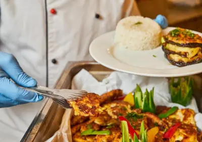 a person holding a fork and a plate of food at Fanadir Bay Beach Resort & Aqua Park in Hurghada