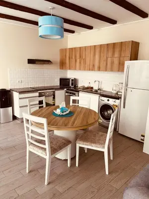 a kitchen with a wooden table and white appliances at 2BR Ground Floor Apartment with Heated Pool in Bali El Gouna in Hurghada
