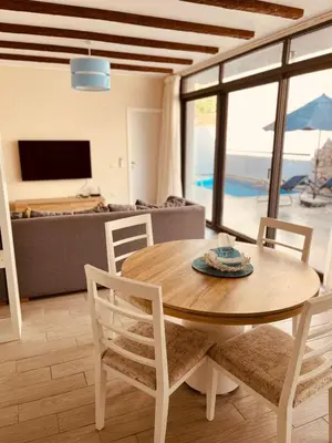 a dining room with a table and chairs and a living room at 2BR Ground Floor Apartment with Heated Pool in Bali El Gouna in Hurghada