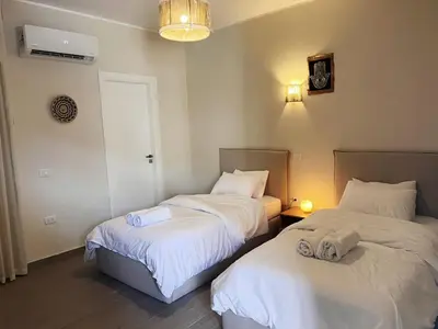two beds in a room with white sheets at 2BR Ground Floor Apartment with Heated Pool in Bali El Gouna in Hurghada