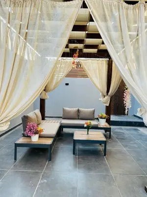 a patio with couches and tables and curtains at 2BR Ground Floor Apartment with Heated Pool in Bali El Gouna in Hurghada
