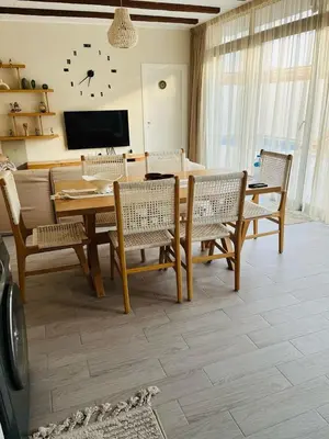 a living room with a table and chairs and a tv at 2BR Ground Floor Apartment with Heated Pool in Bali El Gouna in Hurghada