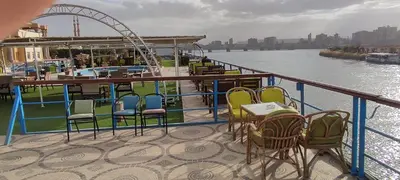 a group of chairs and tables on the deck of a boat at فندق نايل ايليت سوهاج in Qilfāw