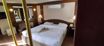 a bedroom with a white bed with a robe on it at فندق نايل ايليت سوهاج in Qilfāw