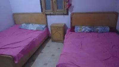 two beds in a room with pink sheets and a night stand at جيست هاوس جبل شيشه سيدون in Maḩaţţat ash Shallāl
