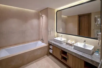 a bathroom with two sinks and a tub and a mirror at Rixos Premium Magawish Bay View in Hurghada