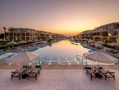 a pool with chairs and umbrellas in a resort at Rixos Premium Magawish Bay View in Hurghada