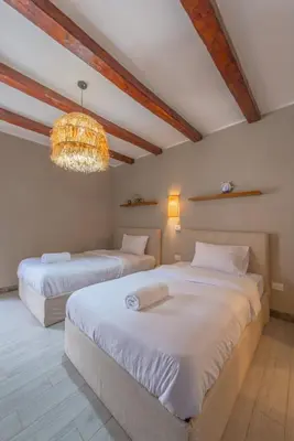 two beds in a room with a chandelier at Elegant 2BR Apartment Heated Pool El Gouna in Hurghada
