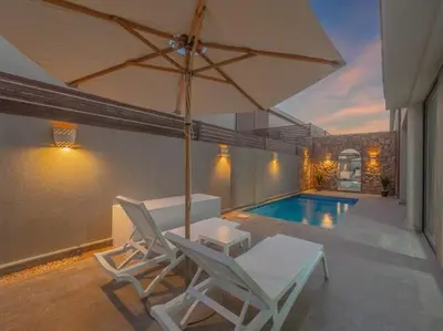 a patio with two chairs and an umbrella and a pool at Elegant 2BR Apartment Heated Pool El Gouna in Hurghada