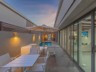 a patio with white tables and chairs and an umbrella at Elegant 2BR Apartment Heated Pool El Gouna in Hurghada