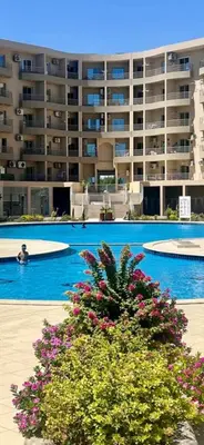 a large apartment building with a swimming pool with flowers at Princess Resort Lovely Studio in Hurghada