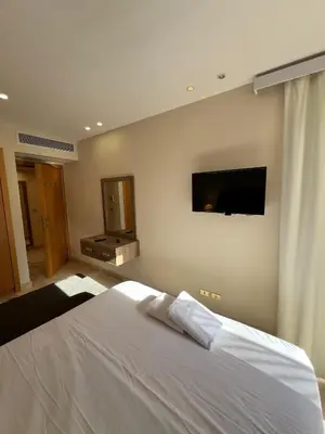 a bedroom with a white bed and a flat screen tv at Ground Floor 1 Bedroom Scrub Unit in El Gouna in Hurghada