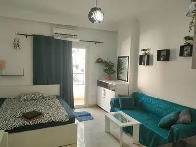 a living room with a blue couch and a bed at Sherathon studio Pavel in Hurghada