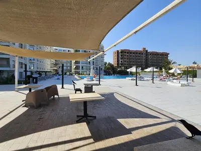 a patio with tables and chairs and a pool at Scandic Resort Hurghada App-C310 in Hurghada