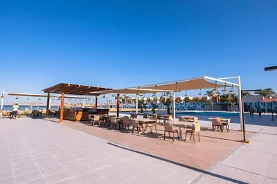 a patio with tables and chairs next to a pool at Scandic Resort Hurghada App-C310 in Hurghada