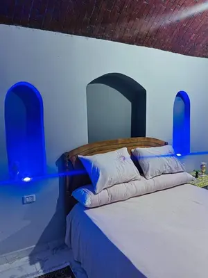 a bedroom with a bed with a wooden headboard and pillows at Adam Guesthouse in Al Kawāmil Qiblī