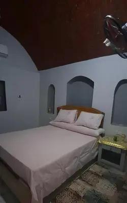 a bedroom with a large white bed and a table at Adam Guesthouse in Al Kawāmil Qiblī