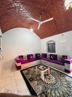 a living room with a purple couch and a table at Adam Guesthouse in Al Kawāmil Qiblī