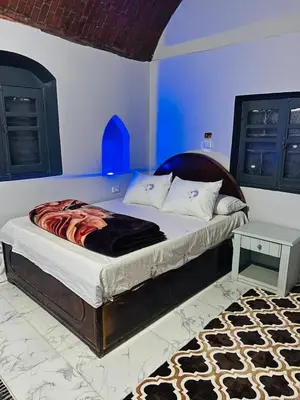 a bedroom with a large bed with a blue wall at Adam Guesthouse in Al Kawāmil Qiblī