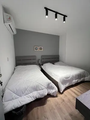 two beds in a bedroom with white sheets at Sholan El Gouna 2 Bedroom Apartment in Hurghada