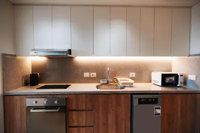 a kitchen with white cabinets and a sink and a microwave at Tranquil Terrace Studio at Ancient Sands in Hurghada