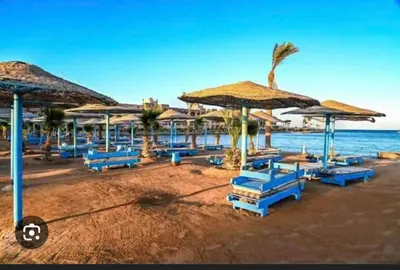 a beach with blue chairs and umbrellas and the ocean at tiba golden resort in Hurghada