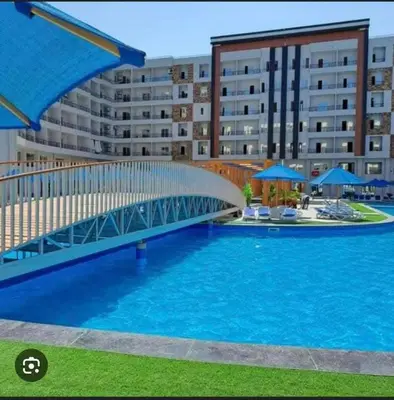 a bridge over a swimming pool in front of a building at tiba golden resort in Hurghada