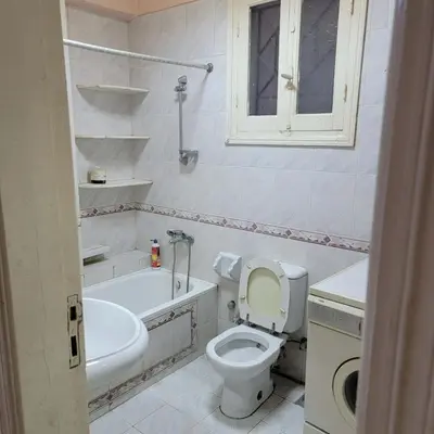 a bathroom with a toilet and a tub and a sink at OS & MA Luxor APT in Luxor