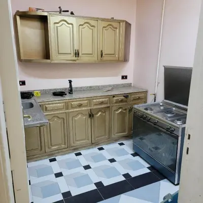 a kitchen with wooden cabinets and a sink at OS & MA Luxor APT in Luxor