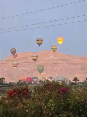 a group of hot air balloons flying over a mountain at Harmonia House in Al Karnak